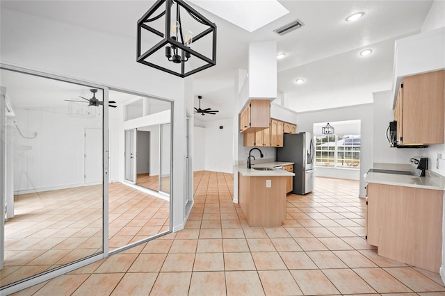 kitchen featuring light tile patterned floors, kitchen peninsula, appliances with stainless steel finishes, ceiling fan with notable chandelier, and sink