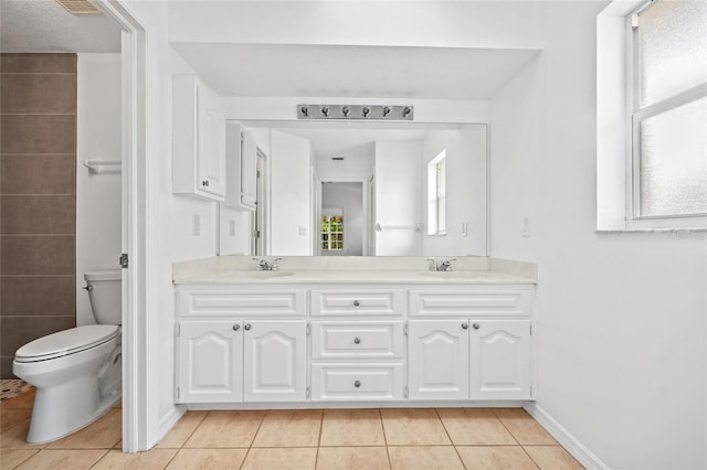 bathroom with toilet, vanity, and tile patterned flooring