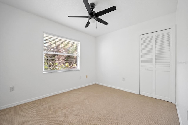 unfurnished bedroom featuring ceiling fan, light colored carpet, and a closet