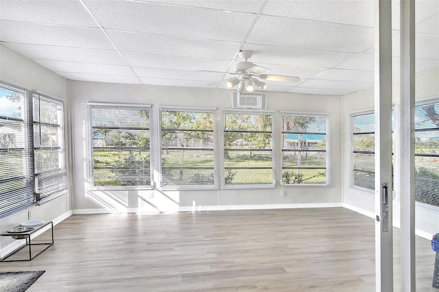 unfurnished sunroom with ceiling fan, a drop ceiling, and a healthy amount of sunlight