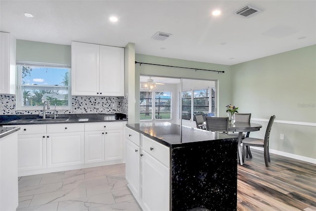 kitchen featuring tasteful backsplash, ceiling fan, a center island, and white cabinets