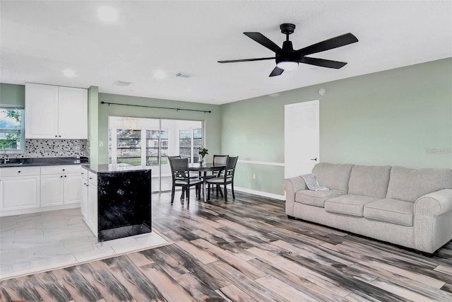 living room featuring ceiling fan, light hardwood / wood-style floors, sink, and a wealth of natural light