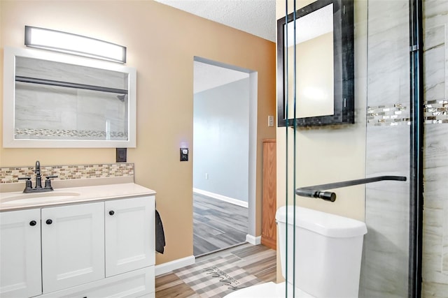 bathroom with tasteful backsplash, a textured ceiling, toilet, vanity, and hardwood / wood-style flooring