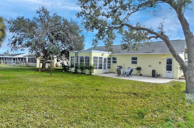 back of property with a lawn, a patio area, and a sunroom