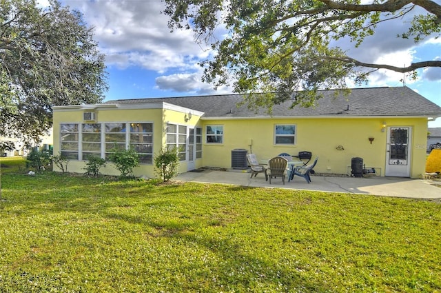 rear view of house featuring a sunroom, a fire pit, a yard, central AC, and a patio area