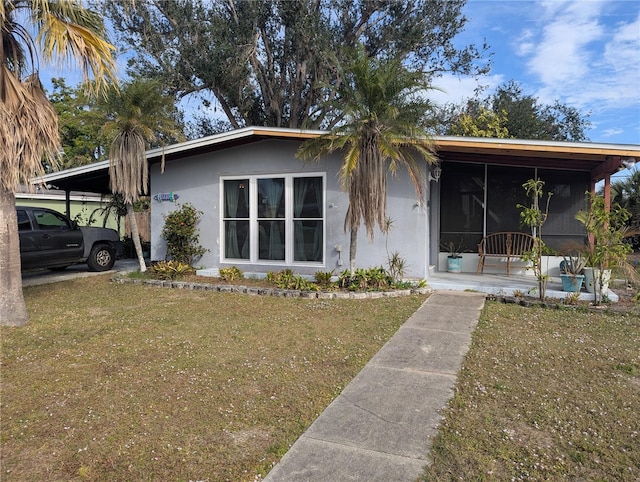 view of front of home with a front yard, an attached carport, and stucco siding