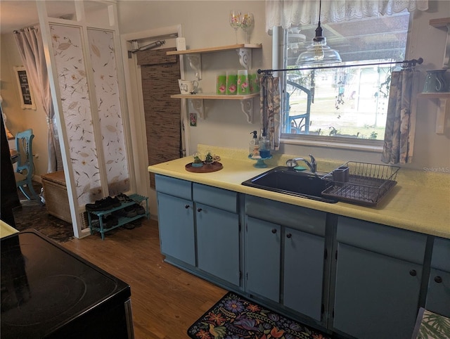 kitchen with sink, blue cabinets, black electric range oven, pendant lighting, and dark wood-type flooring