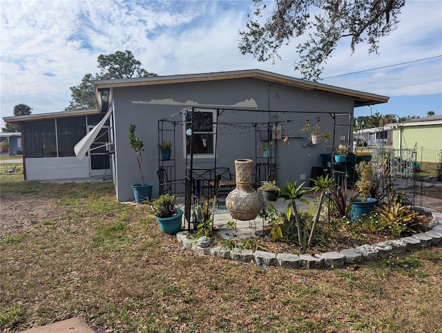 rear view of property featuring an outdoor fire pit and a sunroom