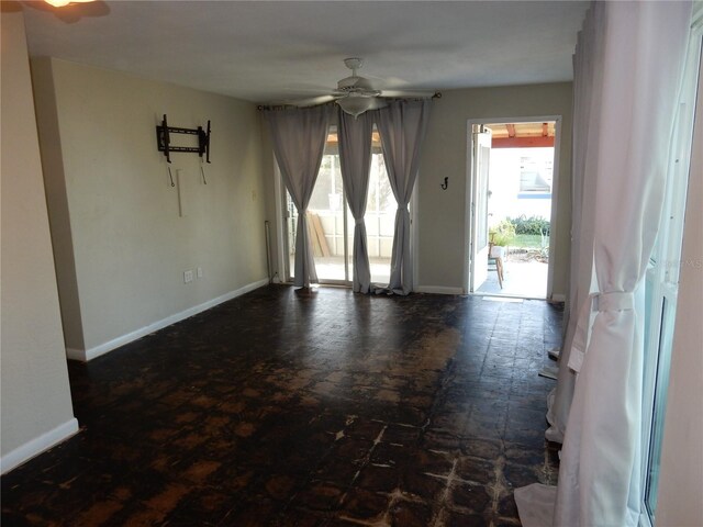 empty room featuring ceiling fan and baseboards