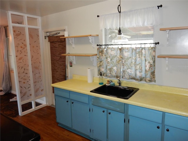 kitchen with blue cabinetry, light countertops, a sink, and decorative light fixtures