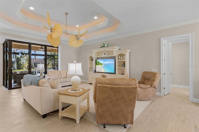 living room with ceiling fan, ornamental molding, a tray ceiling, and light wood-type flooring