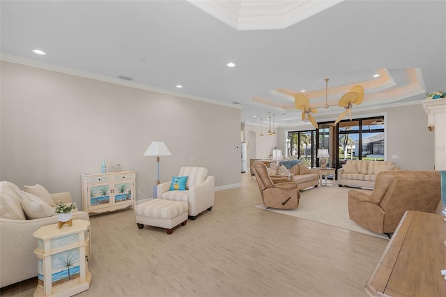 living room featuring light hardwood / wood-style floors, crown molding, and a raised ceiling