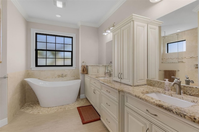 bathroom with a tub to relax in, crown molding, tile patterned floors, vanity, and tile walls