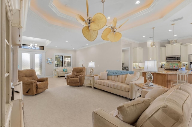 living room featuring a raised ceiling, light carpet, crown molding, french doors, and ceiling fan with notable chandelier