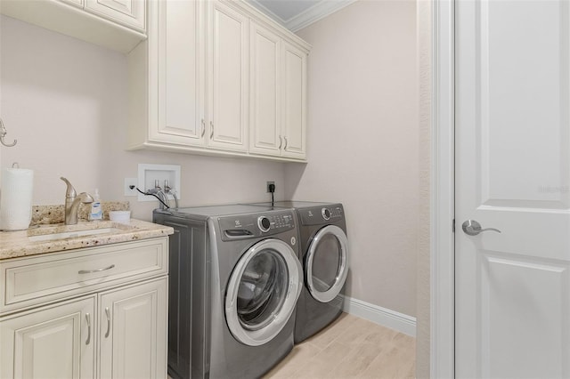 laundry area featuring cabinets, separate washer and dryer, crown molding, and sink