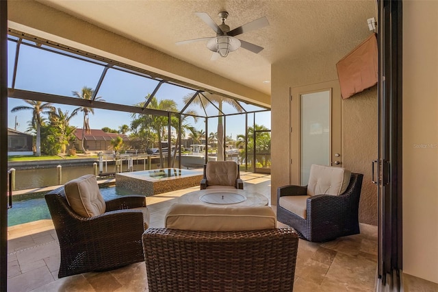 sunroom with ceiling fan and a water view