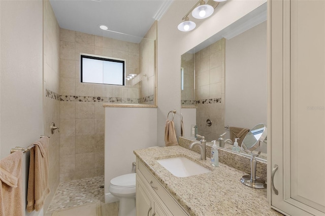 bathroom featuring toilet, tiled shower, and vanity