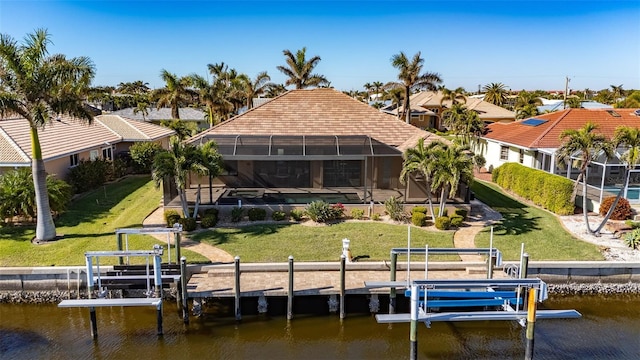 back of property with a yard, a water view, and glass enclosure