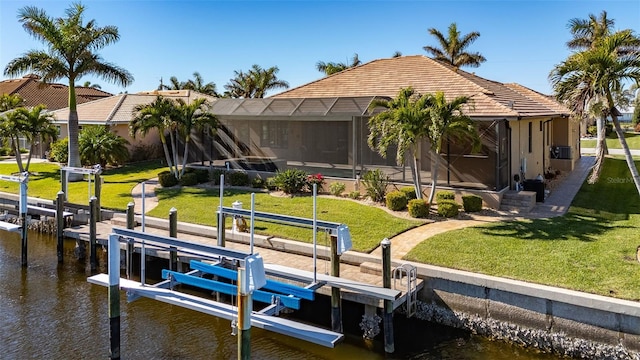 dock area featuring a lanai, a water view, and a lawn