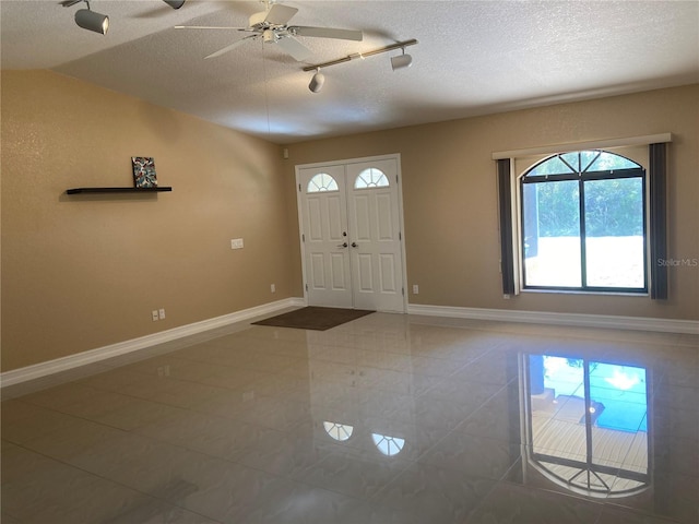 tiled foyer with a textured ceiling, ceiling fan, and a healthy amount of sunlight