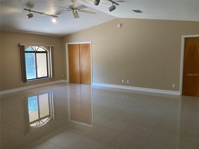 tiled spare room featuring ceiling fan, vaulted ceiling, and a textured ceiling