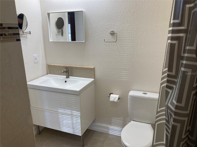 bathroom with toilet, vanity, and tile patterned flooring