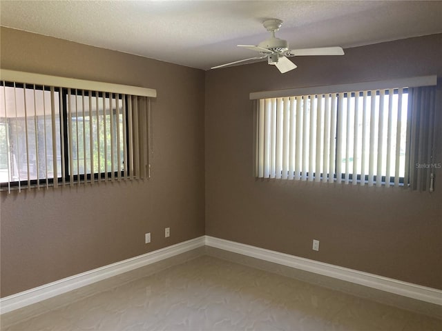 unfurnished room with ceiling fan, a wealth of natural light, and a textured ceiling