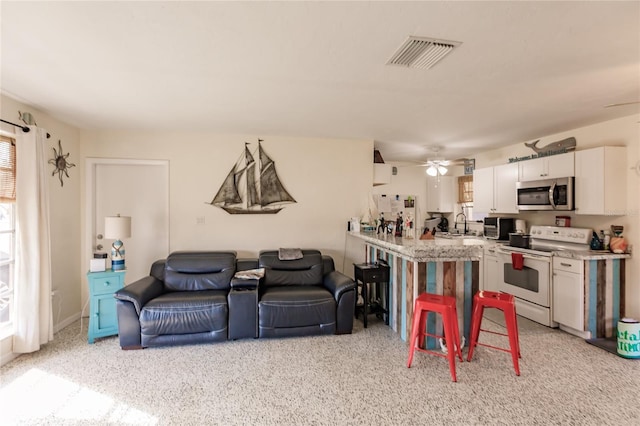 carpeted living room featuring ceiling fan and sink