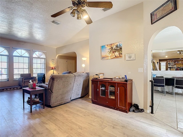 living room featuring a textured ceiling, ceiling fan, and light wood-type flooring