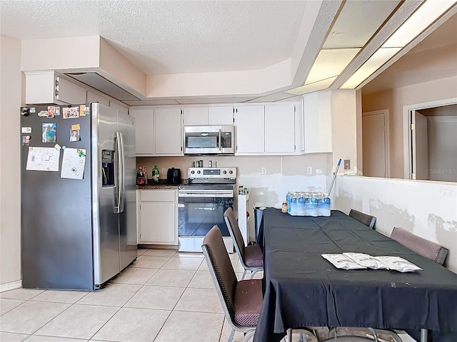 kitchen featuring stainless steel appliances, light tile patterned floors, white cabinets, and a textured ceiling