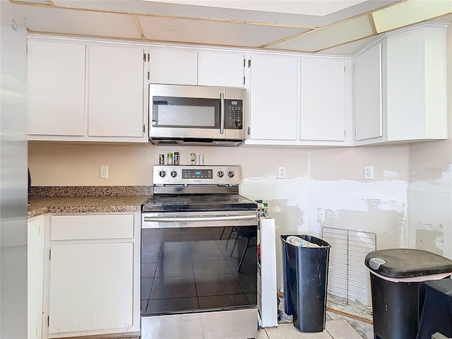 kitchen with light tile patterned floors, stainless steel appliances, and white cabinets