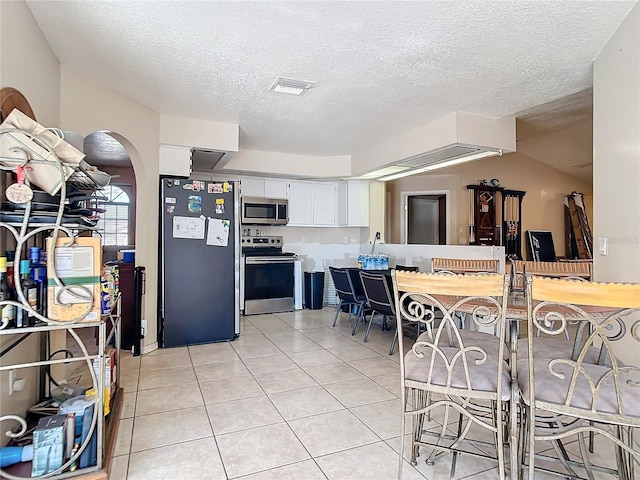 kitchen featuring light tile patterned floors, a textured ceiling, white cabinets, and appliances with stainless steel finishes