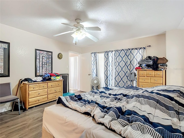 bedroom with a textured ceiling, ceiling fan, and light hardwood / wood-style flooring