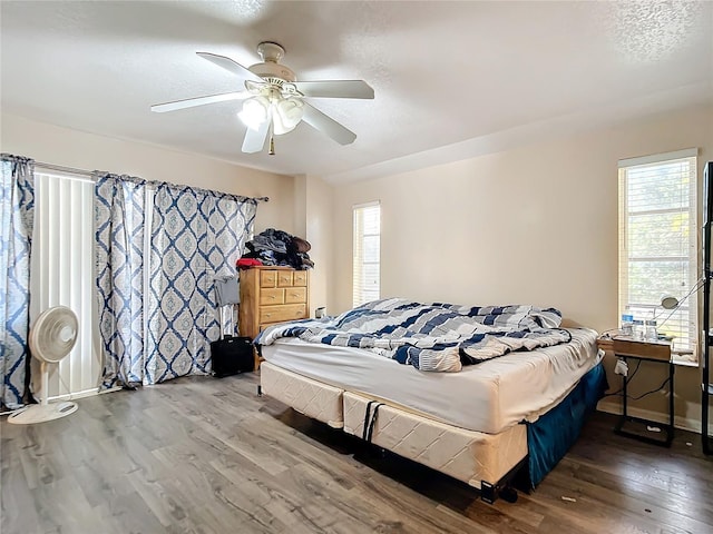 bedroom with a textured ceiling, wood-type flooring, and ceiling fan