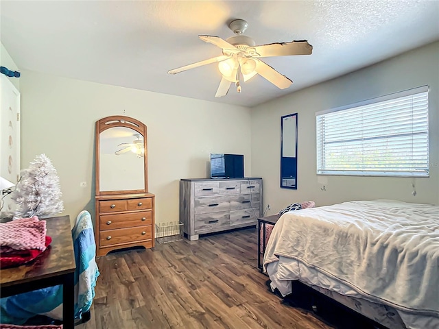 bedroom featuring ceiling fan, dark hardwood / wood-style flooring, and a textured ceiling