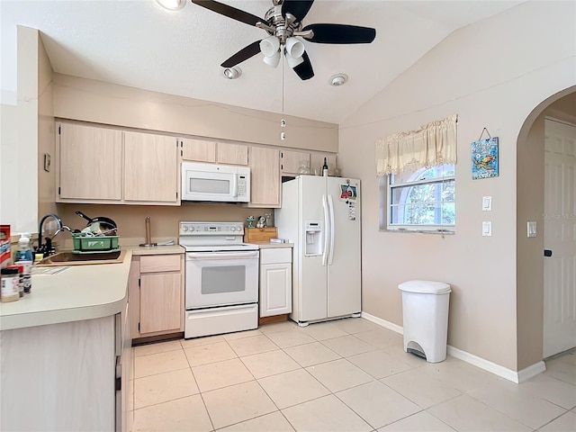 kitchen with sink, white appliances, light tile patterned floors, light brown cabinetry, and vaulted ceiling