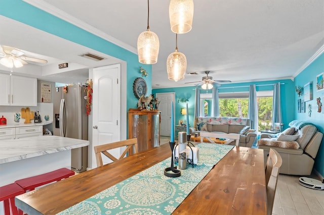 dining space with ceiling fan, crown molding, and light hardwood / wood-style flooring