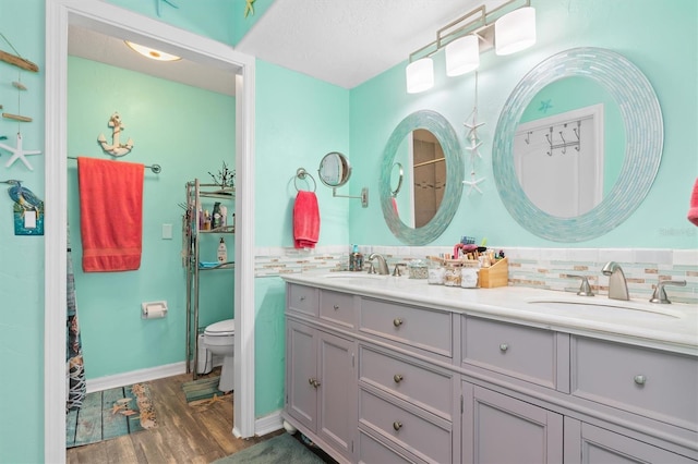 bathroom with tasteful backsplash, vanity, wood-type flooring, and toilet