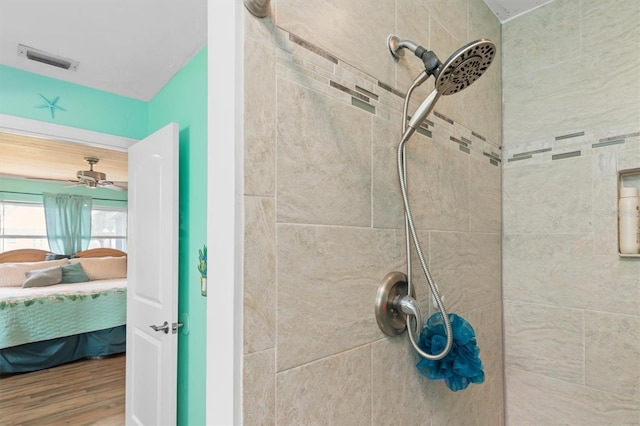 bathroom featuring ceiling fan, hardwood / wood-style flooring, and a tile shower