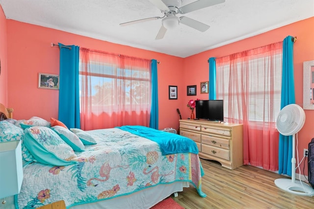 bedroom with ceiling fan, a textured ceiling, and light hardwood / wood-style floors