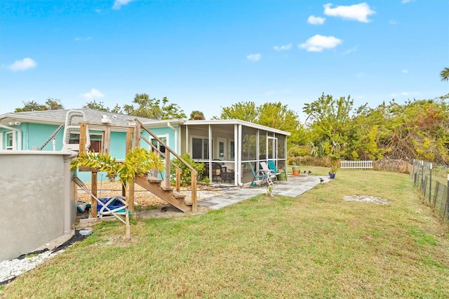 rear view of house featuring a sunroom, a lawn, and a patio