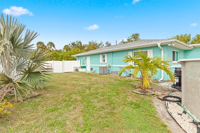 back of house featuring central AC unit and a yard