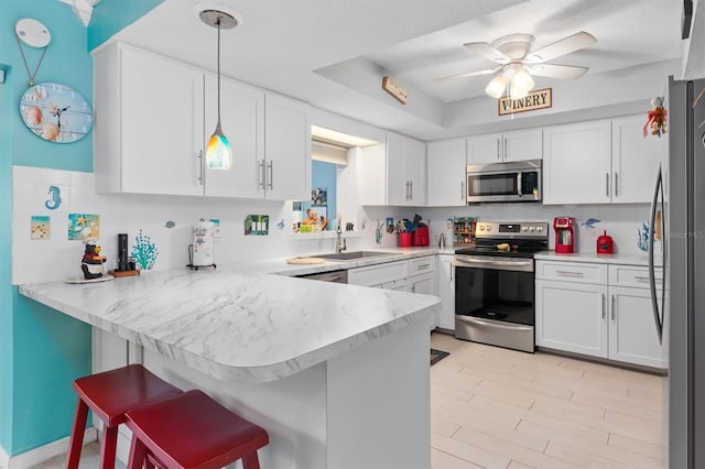 kitchen with a kitchen breakfast bar, white cabinetry, appliances with stainless steel finishes, and kitchen peninsula