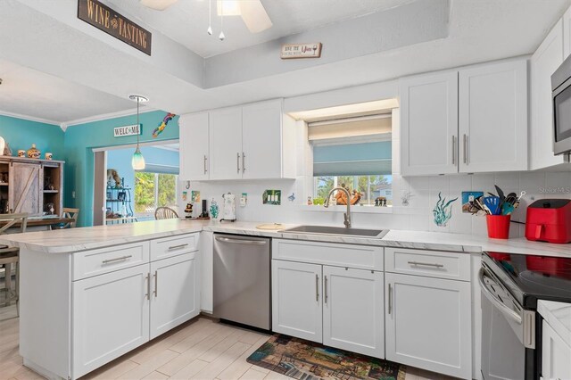 kitchen featuring white cabinetry, kitchen peninsula, appliances with stainless steel finishes, pendant lighting, and sink