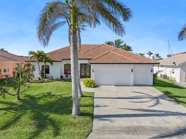 mediterranean / spanish house with a garage, a front lawn, and central air condition unit