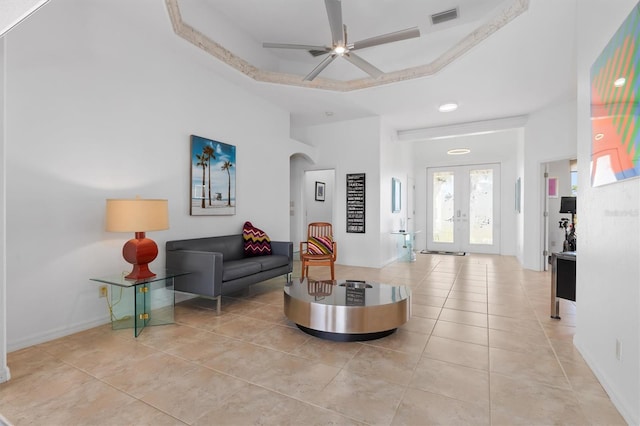 living room featuring ceiling fan, light tile patterned floors, a raised ceiling, and french doors