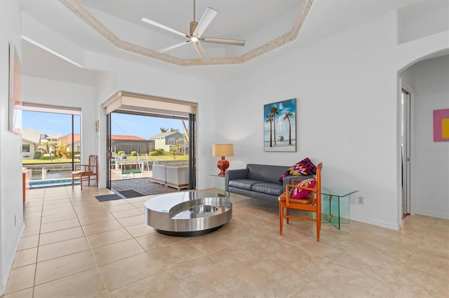 living room with ceiling fan and a raised ceiling