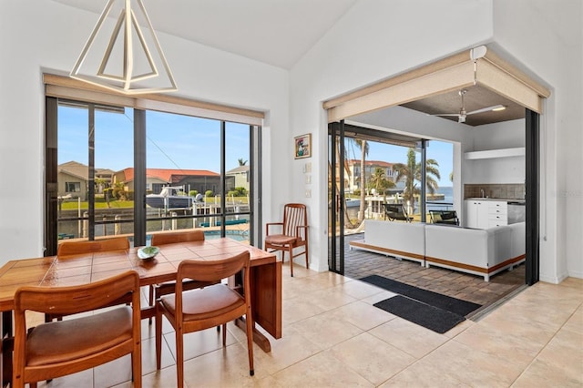 tiled dining area with ceiling fan and vaulted ceiling