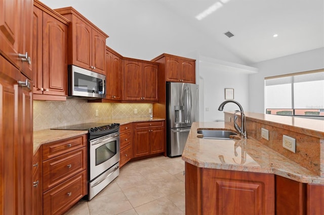 kitchen with lofted ceiling, light stone countertops, sink, and stainless steel appliances