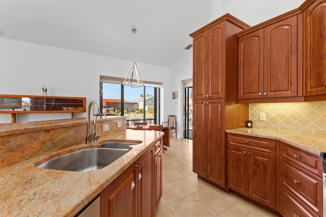 kitchen with decorative light fixtures, tasteful backsplash, sink, light stone countertops, and light tile patterned floors